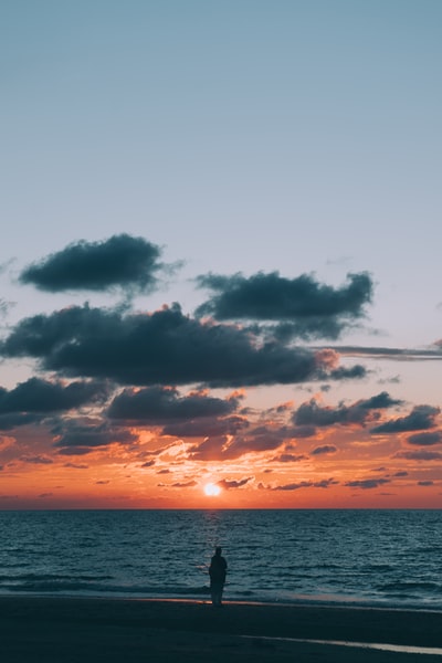 海边的人望着地平线上升起的太阳